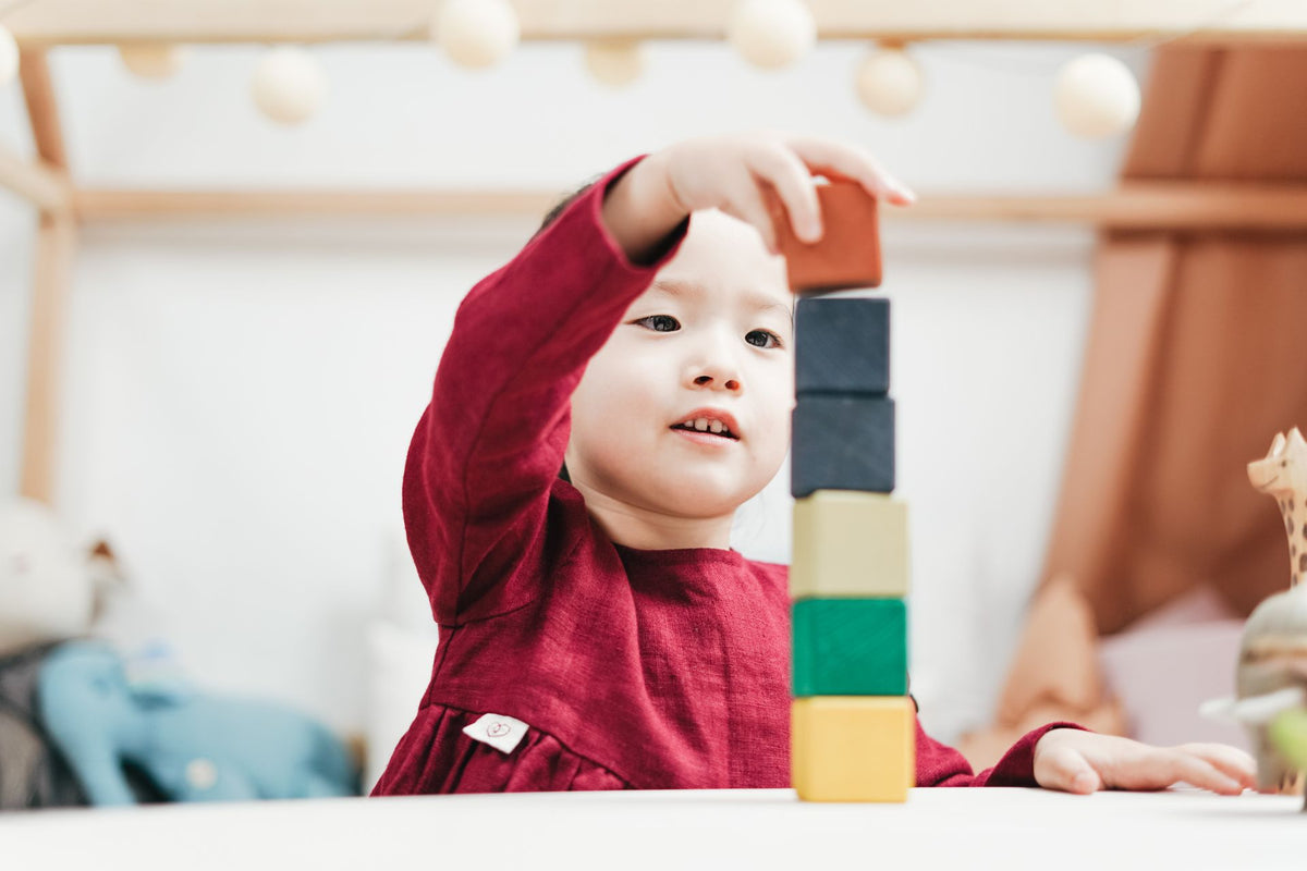 Toddler stacking colourful wooden blocks, an educational toy for early learning
